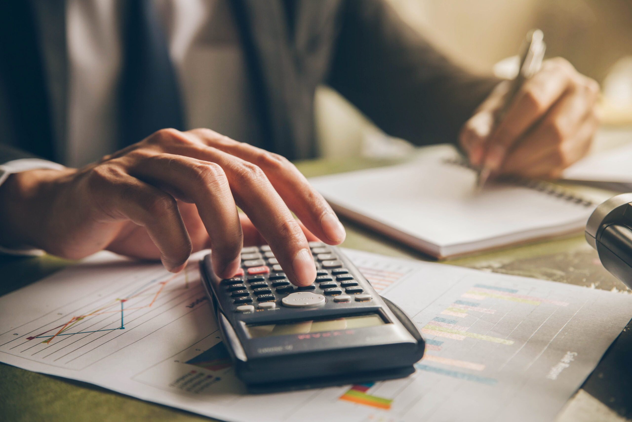 Businessman with calculator counting making notes at office hand is writes in a notebook